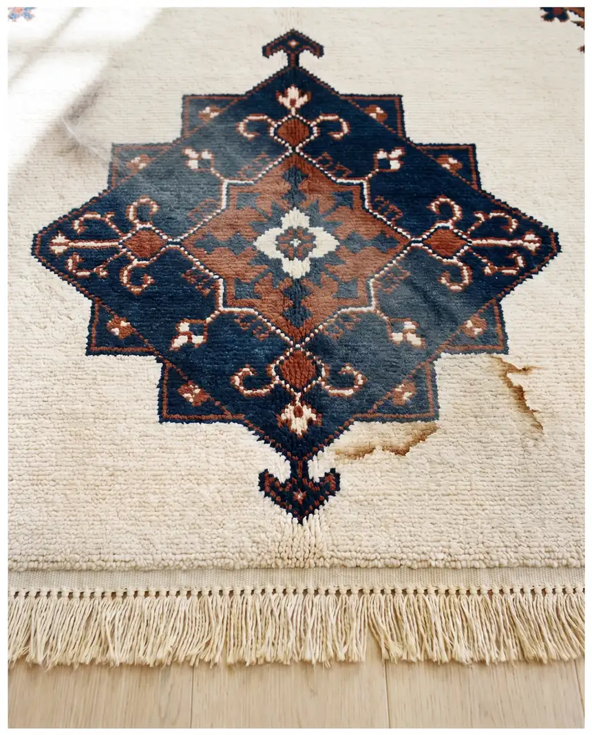 Wool area rug before cleaning: traffic lanes and stains in the cream pile